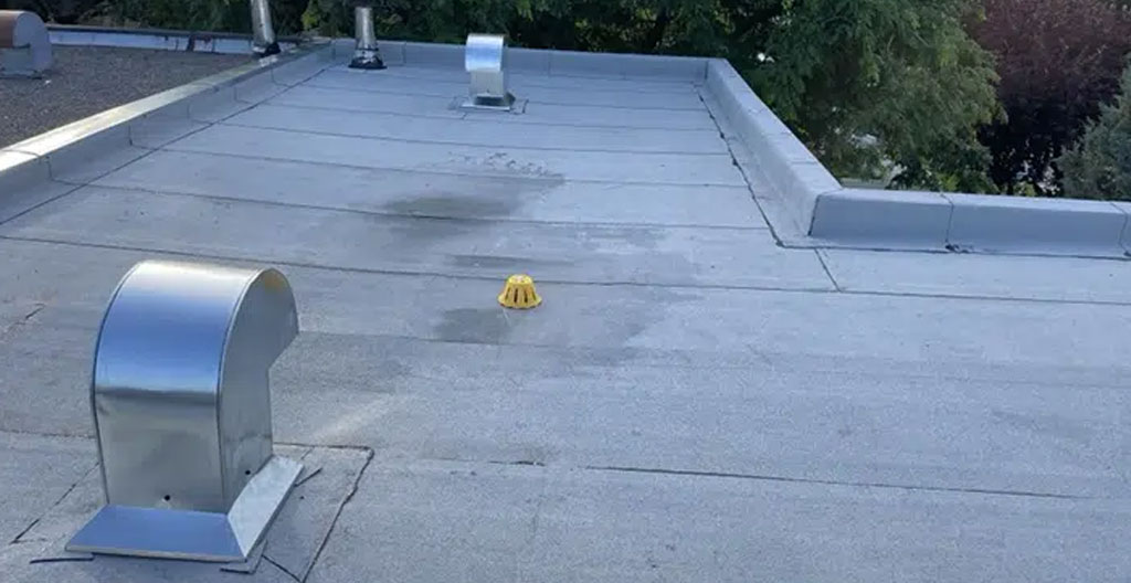 Couvreur certifié inspectant le système de drainage d'un toit plat à Montréal